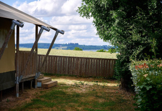 Vista da una tenda safari Villatent Nomad al Camping Les Genêts in Francia, con staccionata e prato.