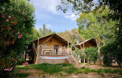 Dos tiendas safari con terrazas y hamaca en Camping Les Pêcheurs, Francia, rodeadas de árboles y vegetación.