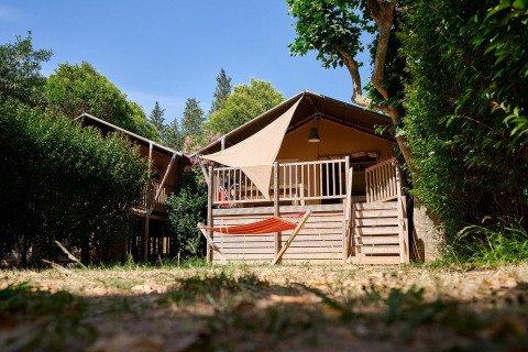 Tienda safari Villatent Nomad en Camping Les Pêcheurs, Francia, vista exterior con hamaca en primer plano.