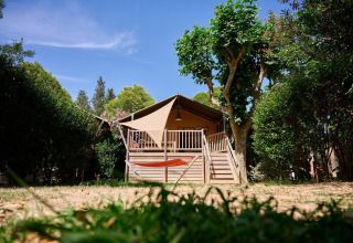 Tienda safari Villatent Nomad en Camping Les Pêcheurs, Francia, rodeada de árboles y hamaca en primer plano.