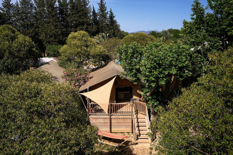 Elegante tienda safari Villatent Nomad entre árboles en Camping Les Pêcheurs, Francia.