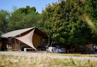 Tienda safari Villatent Nomad en Camping Le Petit Trianon en Francia, rodeada de árboles y naturaleza.