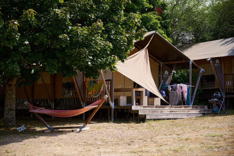Tenda safari Villatent Nomad al Camping Le Petit Trianon in Francia con amaca e terrazza all'aperto.