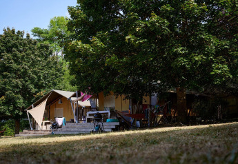 Safaritent Villatent Nomad op Camping Le Petit Trianon in Frankrijk, omgeven door bomen en natuur.
