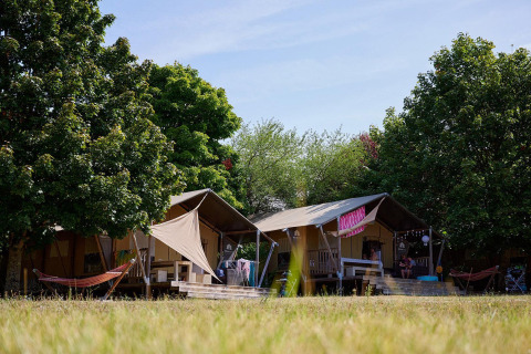 Safaritenten Villatent Nomad op Camping Le Petit Trianon in Frankrijk, omgeven door bomen en natuur.