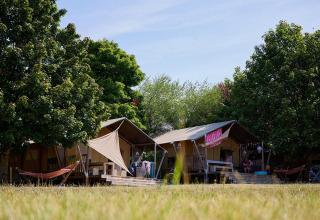 Tiendas safari Villatent Nomad en Camping Le Petit Trianon en Francia, rodeadas de árboles y césped.