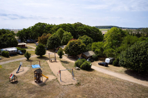 Luchtfoto van Camping Le Petit Trianon in Frankrijk met Villatent Nomad, speeltuin en veel groen.
