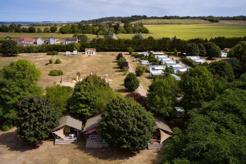 Vista aerea delle tende safari Villatent Nomad al Camping Le Petit Trianon in Francia, circondate da campi verdi.