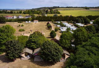 Luftfoto af Villatent Nomad safari telte på Camping Le Petit Trianon i Frankrig med grønne marker omkring.