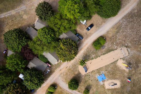 Luchtbeeld van Villatent Nomad op Camping Le Petit Trianon in Frankrijk met tenten, bomen en paden.