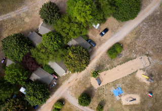 Luchtfoto van Villatent Nomad op Camping Le Petit Trianon in Frankrijk met tenten, bomen en paden.