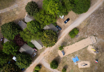 Vista aerea di Villatent Nomad al Camping Le Petit Trianon in Francia, con tende, alberi e sentieri.