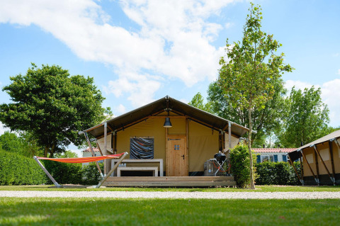 Tenda safari Villatent Nomad al Camping 't Geuldal nei Paesi Bassi con amaca e terrazza in legno.