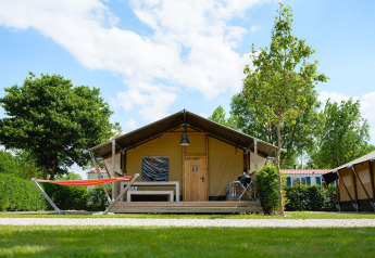 Tenda safari Villatent Nomad al Camping 't Geuldal nei Paesi Bassi con amaca e terrazza in legno.