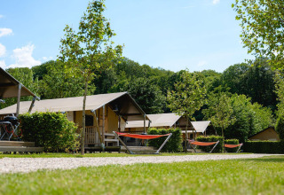 Tiendas safari con terraza y hamacas en Camping 't Geuldal, rodeadas de vegetación en los Países Bajos.
