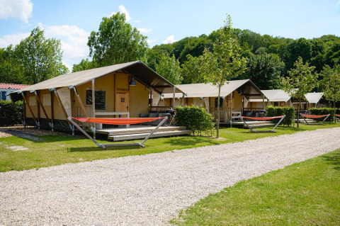 Tende safari Villatent Nomad al Camping 't Geuldal nei Paesi Bassi, circondate da amache e alberi verdi.