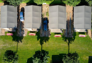 Luchtfoto van vier safaritenten en auto's op Camping 't Geuldal in Nederland, tussen groene grasvelden.