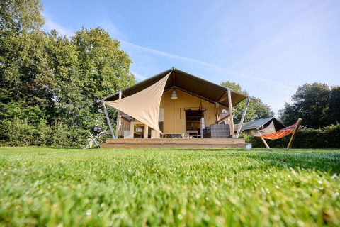 Tienda safari Villatent Nomad en Camping de Papillon, Países Bajos, con hamaca y césped verde brillante.