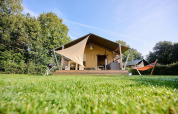 Tienda safari Villatent Nomad en Camping de Papillon, Países Bajos, con hamaca y césped verde brillante.