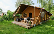 Tienda safari Villatent Nomad con terraza y barbacoa en Parc de Witte Vennen, Países Bajos, rodeada de naturaleza.