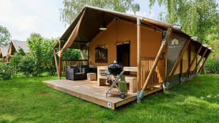 Tente safari Villatent Nomad avec terrasse et barbecue au Parc de Witte Vennen, Pays-Bas, entourée de verdure.
