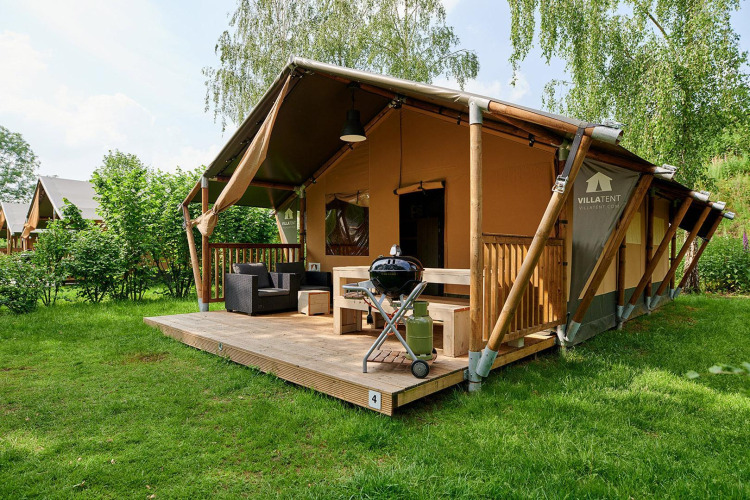 Tienda safari Villatent Nomad con terraza y barbacoa en Parc de Witte Vennen, Países Bajos, rodeada de naturaleza.