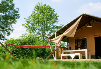 Tienda safari Villatent Nomad en Parc de Witte Vennen, Países Bajos, con hamaca y terraza exterior.