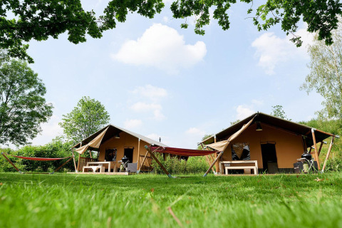 Twee Villatent Nomad safaritenten in Parc de Witte Vennen, Nederland, met hangmatten op het gras.