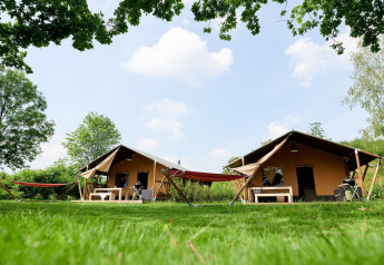 Zwei Villatent Nomad Safarizelte im Parc de Witte Vennen, Niederlande, mit Hängematten auf Rasen.