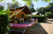 Tienda safari Villatent Nomad en Camping Domaine du Logis, Francia, con hamaca y terraza al aire libre.