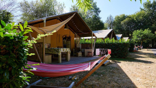 Safaritent Villatent Nomad op Camping Domaine du Logis in Frankrijk met een hangmat en een terras.