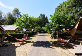 Sentiero tra tende safari Villatent Nomad con amache al Camping Domaine du Logis in Francia.