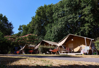 Safari-Zelte auf dem Campingplatz Domaine du Logis in Frankreich, umgeben von Bäumen und Hängematten.