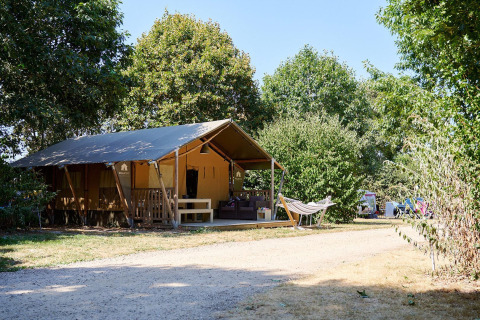 Tienda safari Villatent Nomad con hamaca en Camping La Bretonnière, Francia, rodeada de árboles.