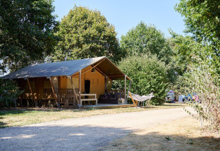 Tienda safari Villatent Nomad con hamaca en Camping La Bretonnière, Francia, rodeada de árboles.