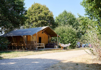 Tienda safari Villatent Nomad con hamaca en Camping La Bretonnière, Francia, rodeada de árboles.