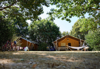 To safari-telte, cykler og hængekøje under træer ved Camping La Bretonnière, Frankrig, Villatent Nomad.