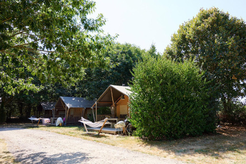 Safaritenten en hangmatten bij Camping La Bretonnière in Frankrijk, omgeven door bomen en groen.