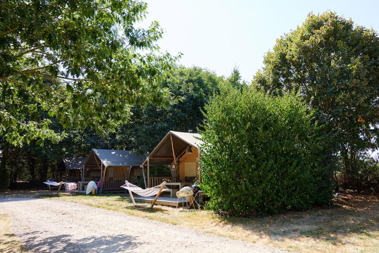 Safari-Zelte und Hängematten auf Camping La Bretonnière in Frankreich mit Bäumen im Hintergrund.