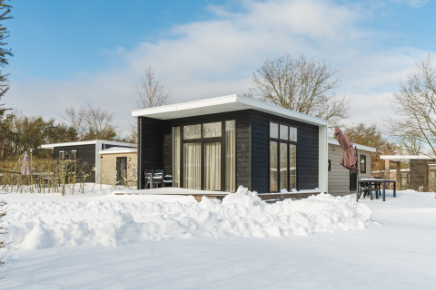 Moderne tiny house Forest Lodge in de sneeuw bij Vakantiepark Hölte, Nederland, met winterse omgeving.