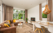 Cozy glamping accommodation featuring a stylish living area, large windows, comfy sofa, and dining table.