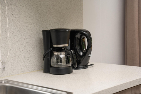 Zwarte koffiemachine en waterkoker op een keukenblad in een glampingaccommodatie, modern ingericht.