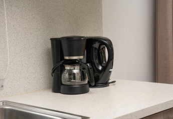 Zwarte koffiezetapparaat en waterkoker op een keukenblad in een glampingverblijf met moderne look.