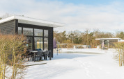 Forest lodge al Vakantiepark Hölte, Paesi Bassi, in inverno con neve, cabine moderne e tavolo all'aperto.