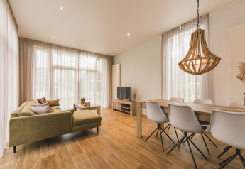 Zona giorno luminosa al Forest Lodge di Vakantiepark Hölte, Paesi Bassi, con arredi moderni in legno.