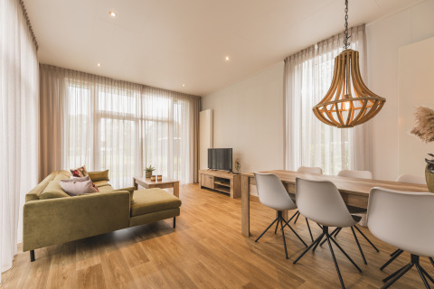 Zona giorno luminosa al Forest Lodge di Vakantiepark Hölte, Paesi Bassi, con arredi moderni in legno.