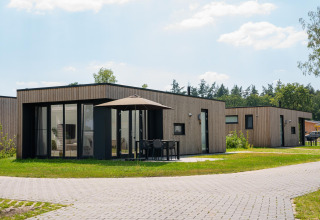 Moderna Oak lodge al Vakantiepark Hölte nei Paesi Bassi con facciata in legno e patio ombreggiato.