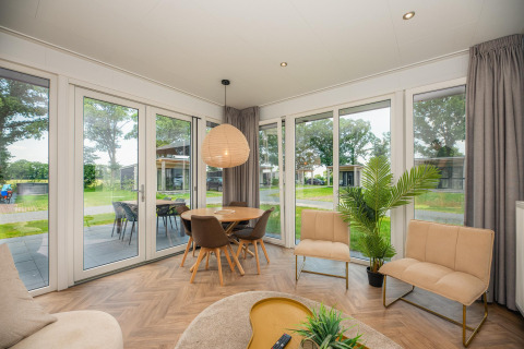 Soggiorno di Oak Lodge al Vakantiepark Hölte, Paesi Bassi, con arredi moderni e vista sul giardino verde.