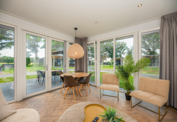 Woonruimte in Oak Lodge te Vakantiepark Hölte, Nederland, met modern interieur en zicht op de tuin.