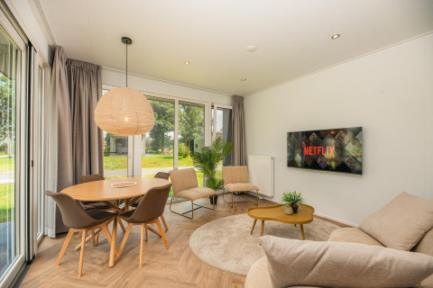 Salon moderne à Oak Lodge, Vakantiepark Hölte, Pays-Bas, avec Netflix à la télévision et grandes fenêtres.